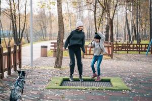 mutter und ihre tochter springen zusammen auf dem trampolin im herbstpark foto