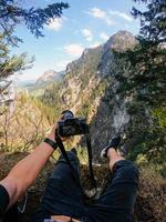 ein fotograf beobachtet mit seiner kamera in der hand von einem berggipfel aus. foto