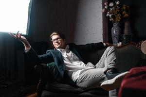 Nahaufnahmeporträt eines attraktiven jungen Mannes, der auf der Couch sich entspannt foto