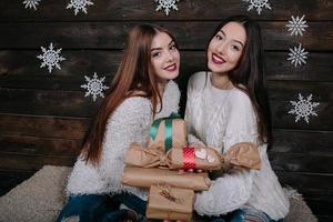 Zwei schöne Mädchen bieten der Kamera Geschenke an foto