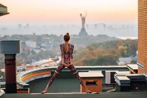 Frau beim Yoga auf dem Dach eines Wolkenkratzers in der Großstadt. foto