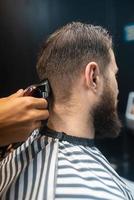 meister im friseursalon macht männerhaarschnitt mit haarschneidemaschine foto