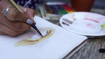 Frauenhand zeichnet menschliches Auge auf Skizzenbuch mit einem Pinsel foto