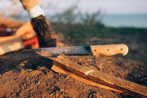 Mann hackt an einem sonnigen Tag Holz mit einem großen Lagerfeuermesser. foto