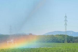 Bewässerungsmaschine auf einem grünen Feld mit einem Regenbogen foto