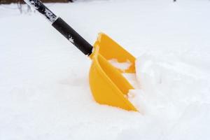 ein Mann, der den Schnee mit der Schaufel in der Nähe des Hauses schaufelt foto