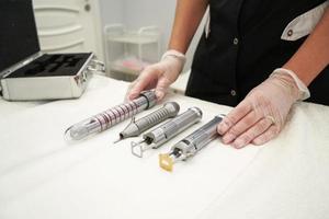 ein Gynäkologe, der Instrumente und Laser für Anti-Aging-Verfahren von Patientinnen vorbereitet foto