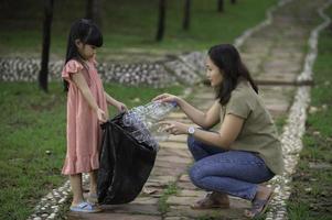 asiatische mutter und tochter helfen bei der karitativen umgebung der müllabfuhr. foto