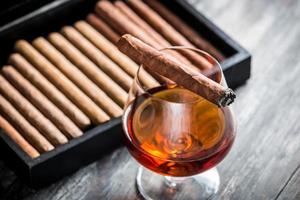 brennende Zigarre auf Glas mit Cognac foto