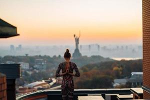 Frau beim Yoga auf dem Dach eines Wolkenkratzers in der Großstadt. foto