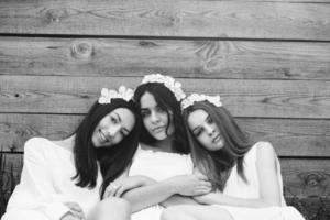 Drei charmante Mädchen in der Nähe eines Holzhauses foto