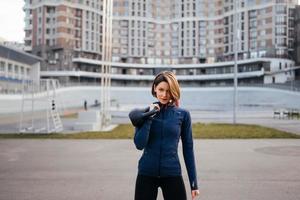 junge Frau, die draußen im Stadion mit einer Kettlebell trainiert foto
