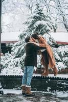 junger Mann und schönes Mädchen küssen sich in einem verschneiten Park foto