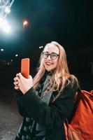 blonde Frau mit Smartphone nachts auf der Straße. foto