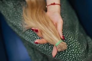 junge frau, die ihr frisch geschnittenes langes braunes haar in pferdeschwänzen hält foto