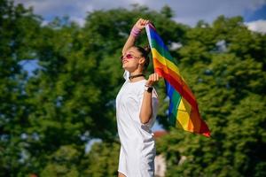 junge frau, die lgbt-stolzfahne im park schwenkt. foto