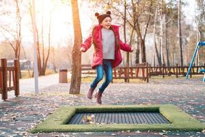 glückliches Schulmädchen, das auf einem kleinen Trampolin im Park springt foto