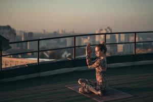 Frau beim Yoga auf dem Dach eines Wolkenkratzers in der Großstadt. foto