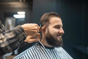 meister im friseursalon macht männerhaarschnitt mit haarschneidemaschine foto