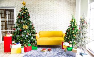 weihnachts- und neujahrsferienkonzept. weihnachtsbaumdekoration mit bändern, kugeln, schneeflocken und ornamenten und geschenkboxen über weißer backsteinmauer bereiten sich auf die nachtparty vor