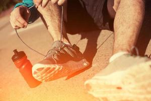 Sportler binden Schnürsenkel an seinen Laufschuhen im Park foto
