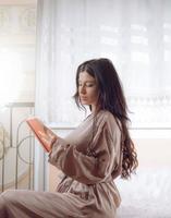 elegantes Mädchen, das ein Buch in der Wohnung liest foto