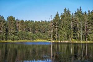 Schönheitslandschaft am Bergsee mit ruhigem Wasser, Baumreflexion und Schönheitshimmel foto