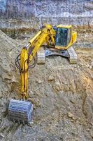 Gelber Bagger mit Schaufel im Einsatz auf der Baustelle. vertikale Ansicht foto