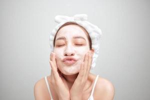 junge asiatische frau, die gesichtslehmmaske über weißem hintergrund anwendet. Beauty-Behandlungen-Konzept. foto