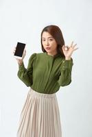 schöne asiatische Wowan zeigt oder präsentiert Handy-Anwendung auf der Hand und ok Zeichen isoliert auf weißem Hintergrund foto