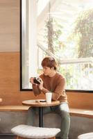 asiatischer mann, der die kamera verwendet, die in einem café sitzt. foto