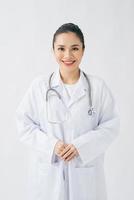 Porträt eines fröhlich lächelnden Arztes in weißer Uniform, der mit gekreuzten Händen auf weißem Hintergrund steht foto