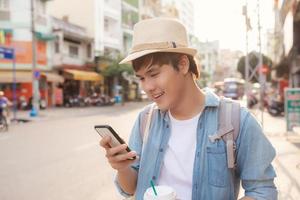 lächelnder junger glücklicher asiatischer männlicher tourist, der im urlaub wandert foto