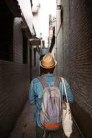 Hipster des jungen Mannes, der mit Rucksack und Hut reist, foto