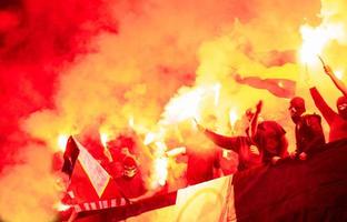 Kroatien, 2022 - Fußball-Hooligans mit Maske, die Fackeln im Feuer halten foto