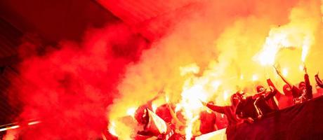 Kroatien, 2022 - Fußball-Hooligans mit Maske, die Fackeln im Feuer halten foto