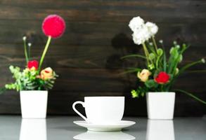 Kaffeetasse und Blumenstrauß aus künstlicher Blumenvase über dem Tisch foto