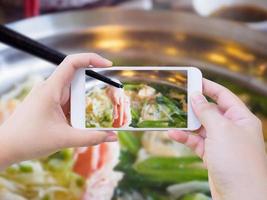 frau, die foto von sukiyaki shabu shabu macht