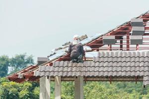 baudachdecker, der dachziegel auf der hausbaustelle installiert foto