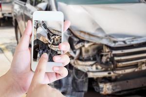 Frau, die ein mobiles Smartphone verwendet, um ein Foto eines Autounfalls zu machen, der für die Versicherung beschädigt wurde