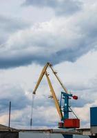 Große Turmdrehkrane stehen in einem Flusshafen vor einem bewölkten Himmel. foto