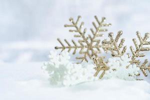 weihnachten des winters - weihnachtsschneeflocken auf schnee, winterferienkonzept. weiße und goldene Schneeflockendekorationen im Schneehintergrund foto