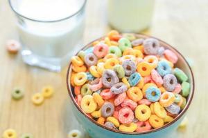 schüssel mit buntem kindermüsli und milch isoliert auf holztisch mit textraum foto