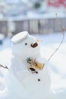 Grußkarte der frohen Weihnachten und des guten Rutsch ins Neue Jahr mit Kopienraum. Viele Schneemänner, die in der Winterweihnachtslandschaft stehen. Winterhintergrund. Schneemann mit trockener Blume und Kiefer. Frohe Feiertage und Feiern. foto