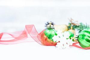 weihnachten des winters - weihnachtskugeln mit band auf schnee, winterferienkonzept. weihnachtsgrüne kugeln, goldene kugeln, kiefern- und schneeflockendekorationen im schneehintergrund foto