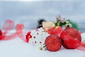 weihnachten des winters - weihnachtskugeln mit band auf schnee, winterferienkonzept. weihnachtsrote kugeln, goldene kugeln, kiefern- und schneeflockendekorationen im schneehintergrund foto