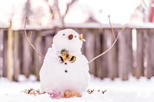 Grußkarte der frohen Weihnachten und des guten Rutsch ins Neue Jahr mit Kopienraum. Viele Schneemänner, die in der Winterweihnachtslandschaft stehen. Winterhintergrund. Schneemann mit trockener Blume und Kiefer. Frohe Feiertage und Feiern. foto