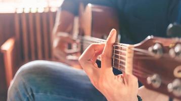 nahaufnahme der hände und finger eines männlichen musikers, der eine akustische gitarre spielt. musikalisches gitarreninstrument für erholung oder entspannendes hobby-leidenschaftskonzept. foto
