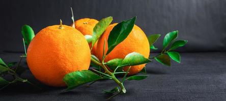 frische Orange und Blatt auf schwarzem Hintergrund foto