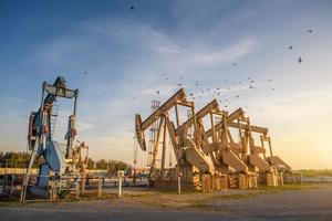 Bohrinsel oder Ölfeld, morgens oder abends laufen Ölpumpen, die Ölpumpe und der schöne Sonnenuntergang oder Sonnenaufgang der Pumpeinheit. foto